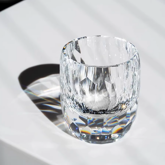 Hand cut crystal whiskey glass with faceted design on white surface with shadow