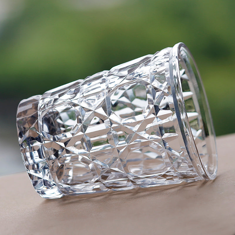 Hand cut crystal whiskey glass with geometric facets resting on its side