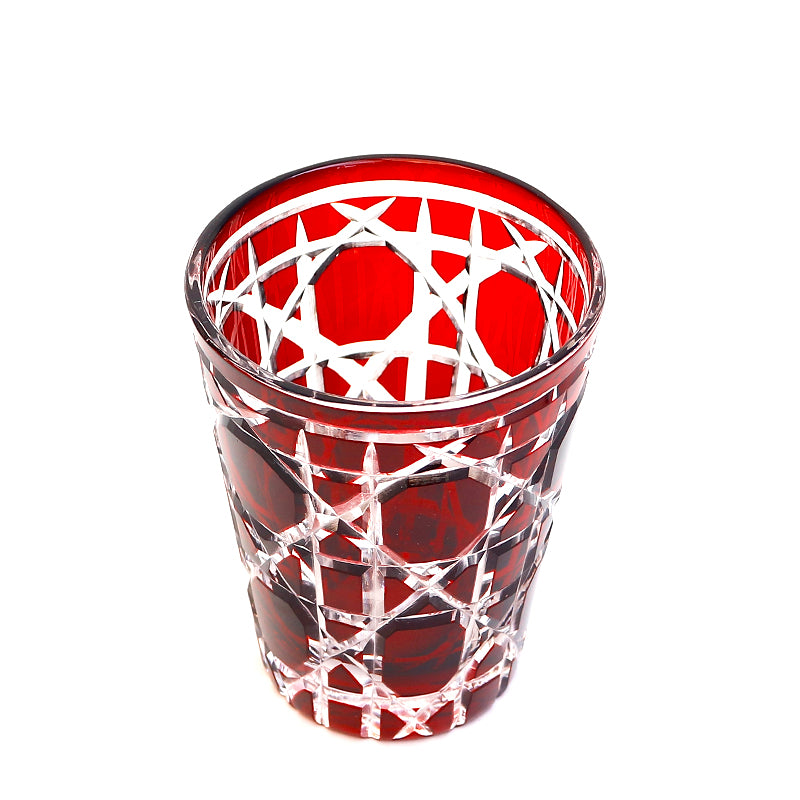 Red hand cut crystal whiskey glass with geometric faceted pattern on white background