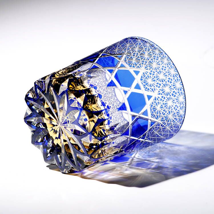 Hand cut blue crystal whiskey glass with intricate geometric patterns and brilliant facets