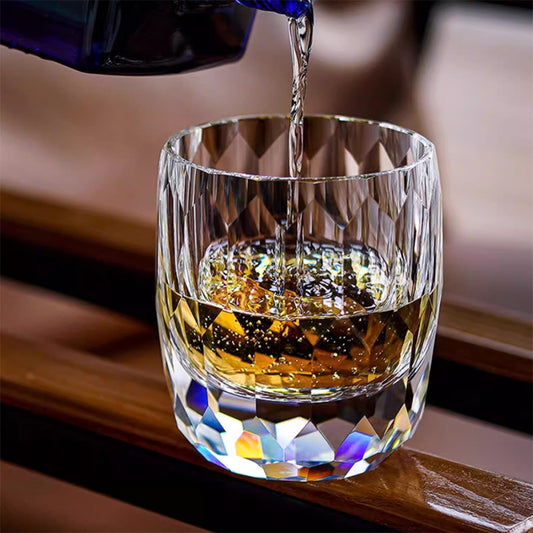 Hand cut crystal whiskey glass with faceted design being filled with liquor