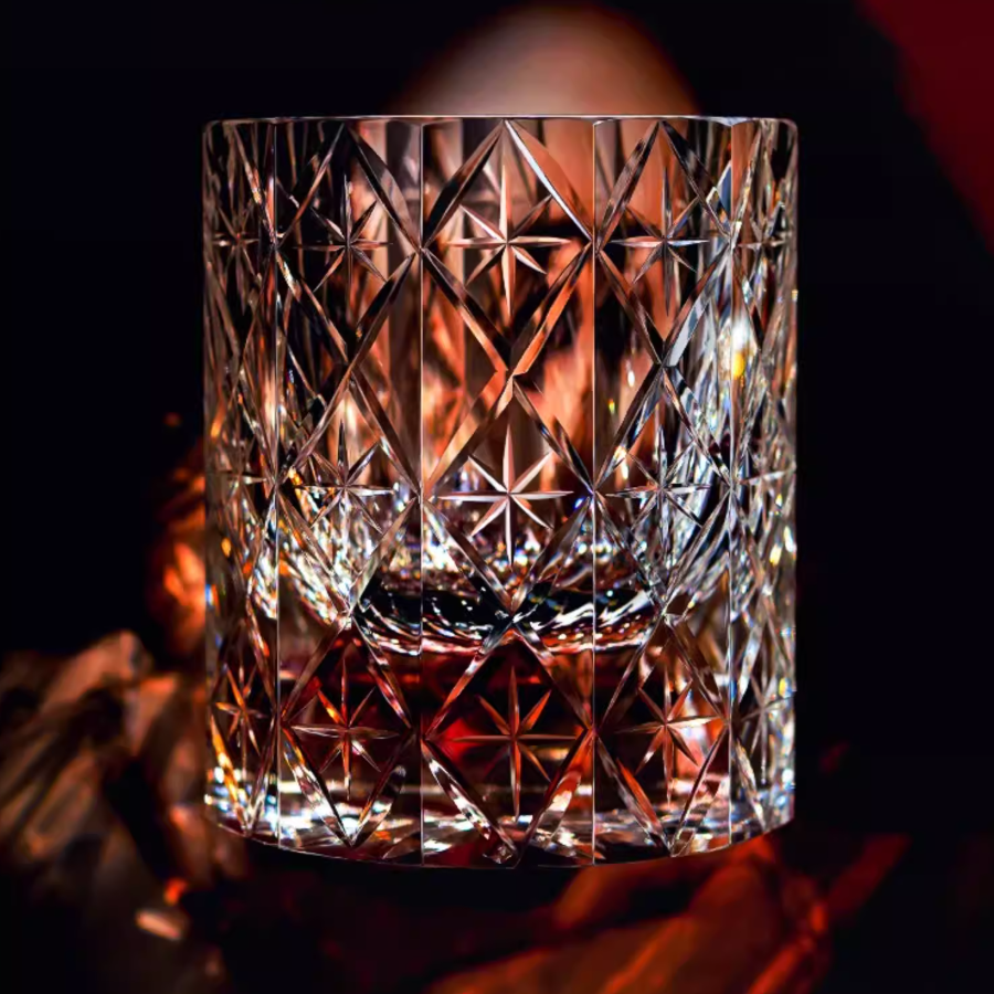 Hand cut crystal whiskey glass with intricate geometric facets and amber liquid