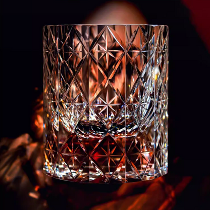 Hand cut crystal whiskey glass with intricate geometric facets and amber liquid