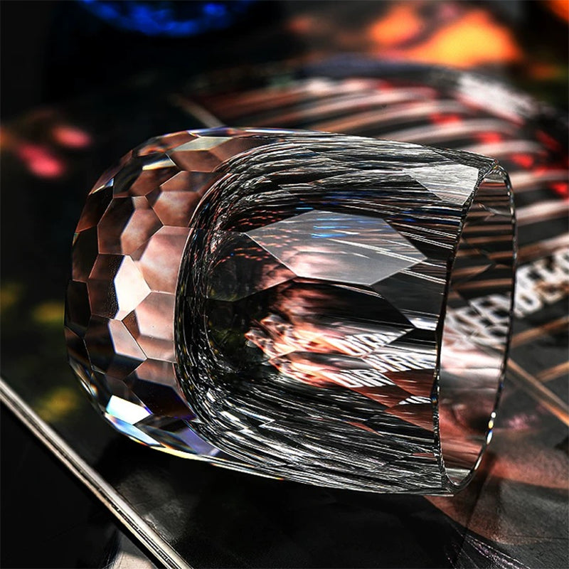 Hand cut crystal whiskey glass with faceted design on a reflective surface