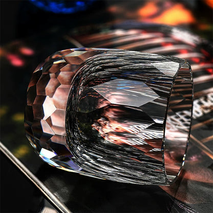 Hand cut crystal whiskey glass with faceted design on a reflective surface