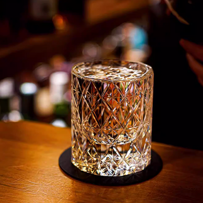 Hand cut crystal whiskey glass with intricate facets on a wooden bar surface