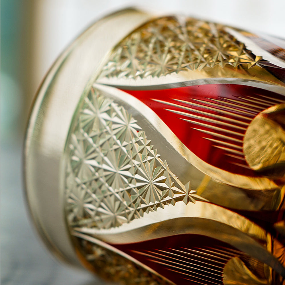 Close-up of hand cut crystal whiskey glass with intricate geometric and red accent design