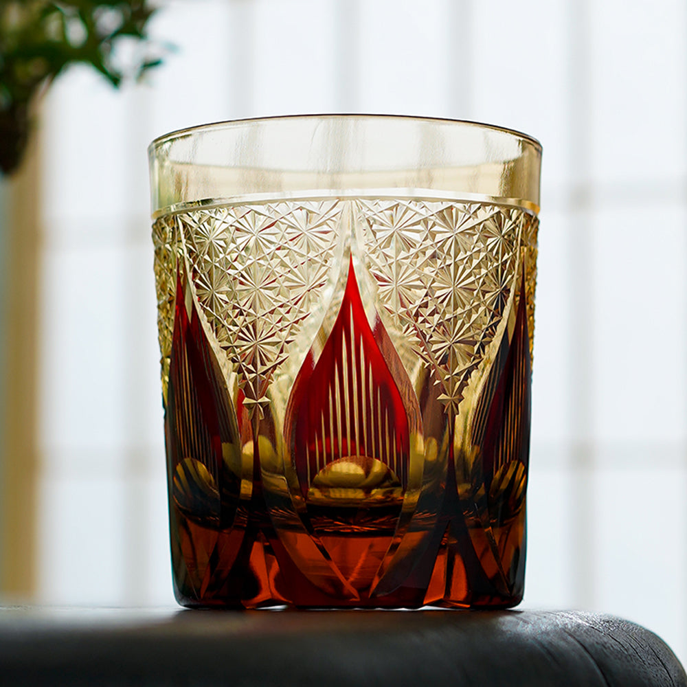 Hand cut crystal whiskey glass with intricate geometric pattern and amber liquid