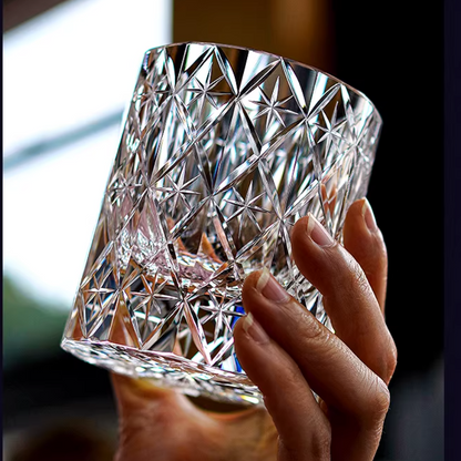 Hand holding a hand cut crystal whiskey glass with intricate star pattern facets