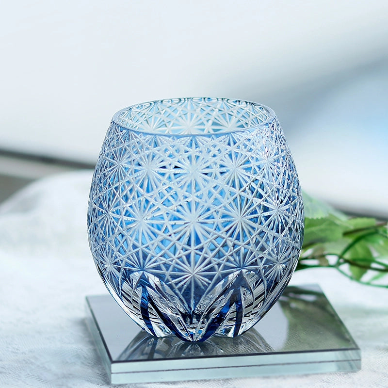 Blue hand cut crystal whiskey glass with intricate geometric pattern on glass coaster