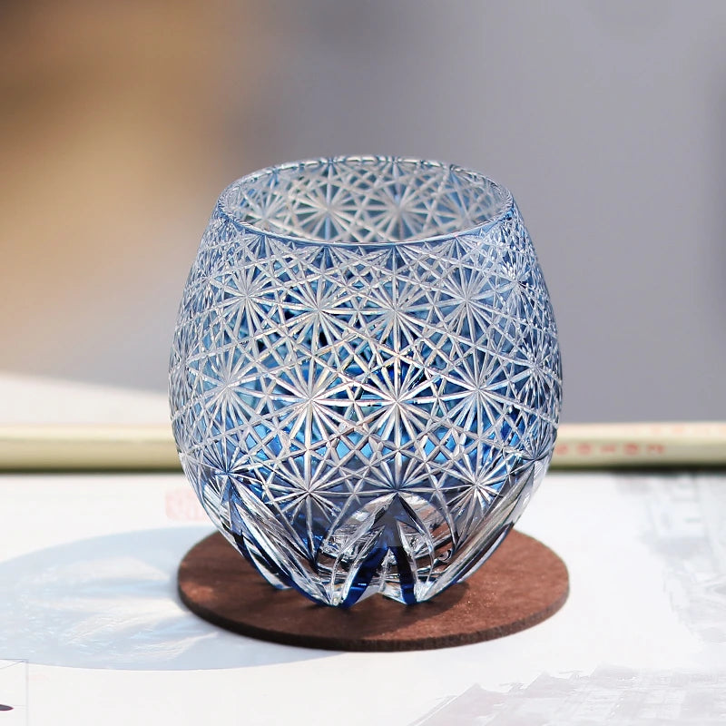 Hand cut crystal whiskey glass with intricate geometric pattern on a coaster