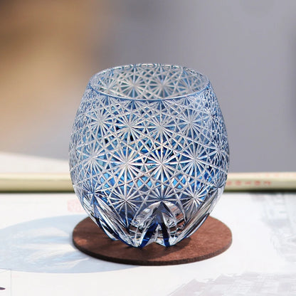 Hand cut crystal whiskey glass with intricate geometric pattern on a coaster
