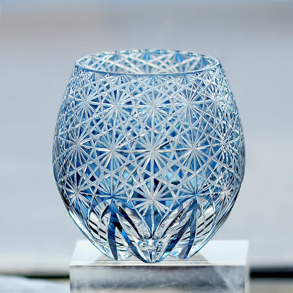 Hand cut crystal whiskey glass with intricate geometric facets on a reflective surface