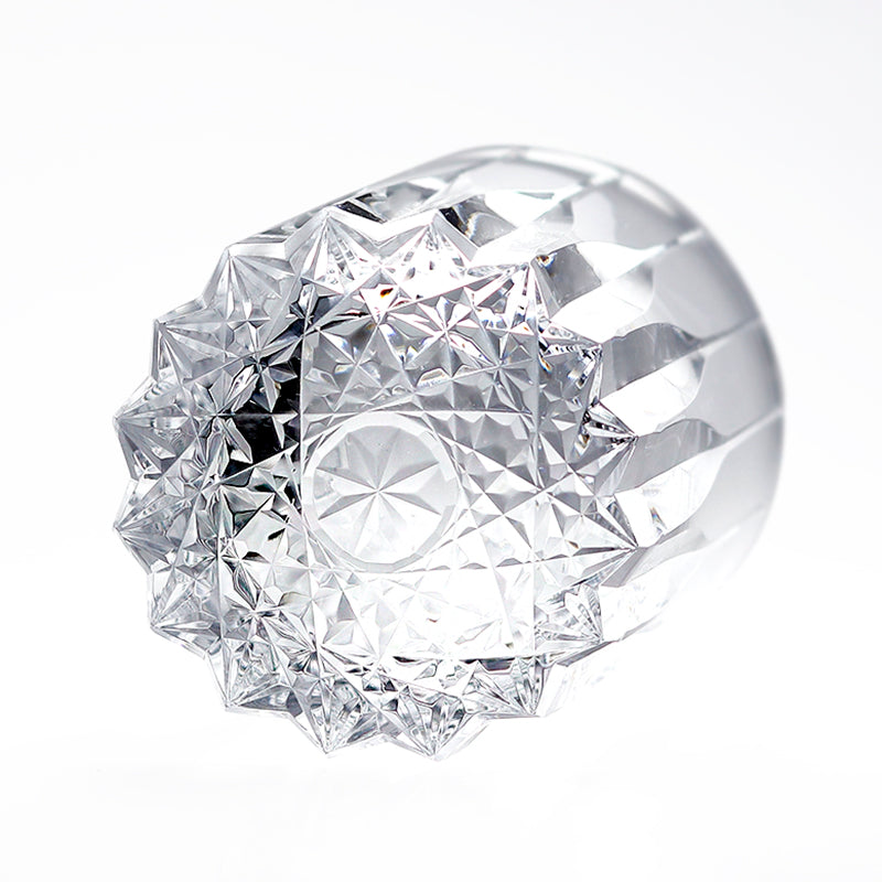 Bottom view of transparent hand‑fluted glass tumbler, showcasing star‑faceted carved base structure